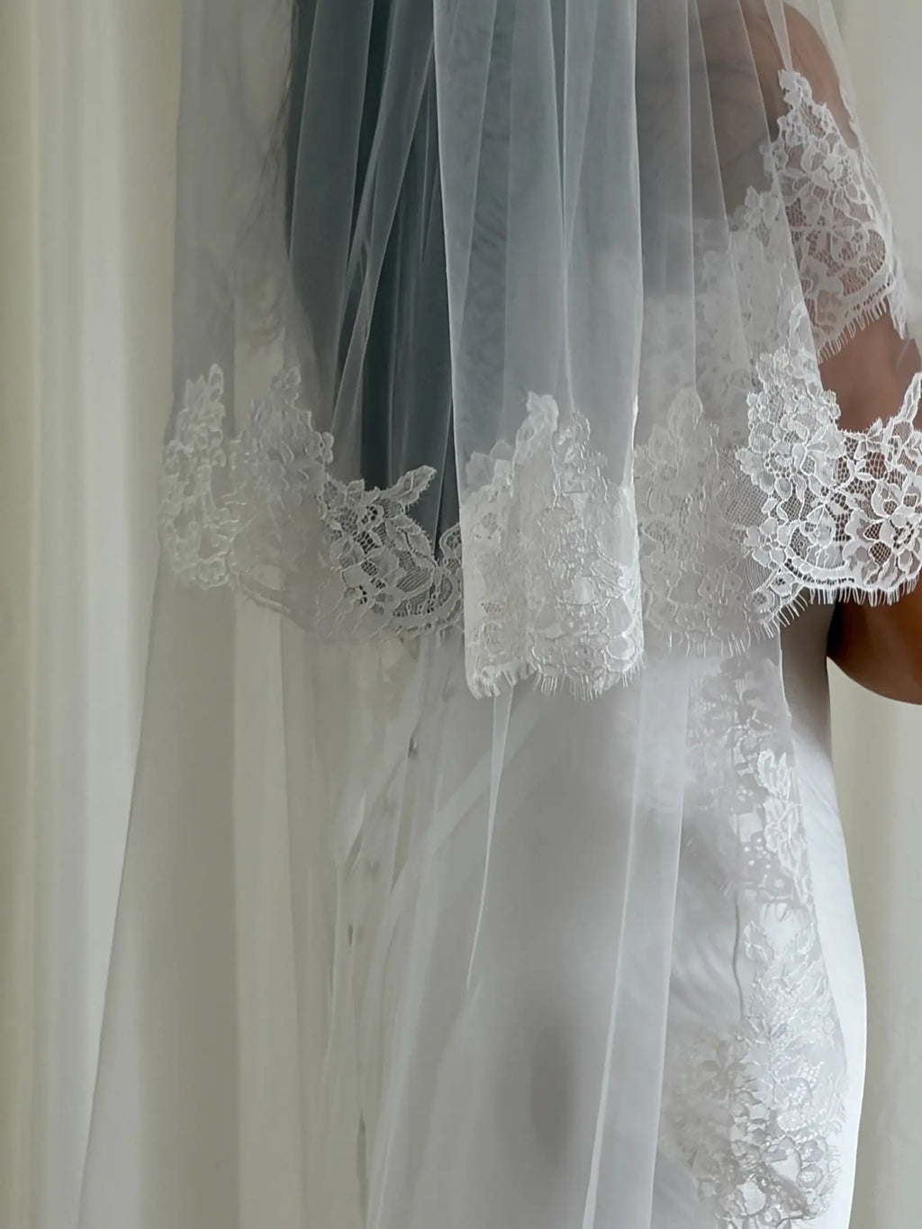 Soft off-white cathedral bridal veil made from lightweight tulle with delicate lace trim and a drop blusher, perfect for a dreamy, romantic look