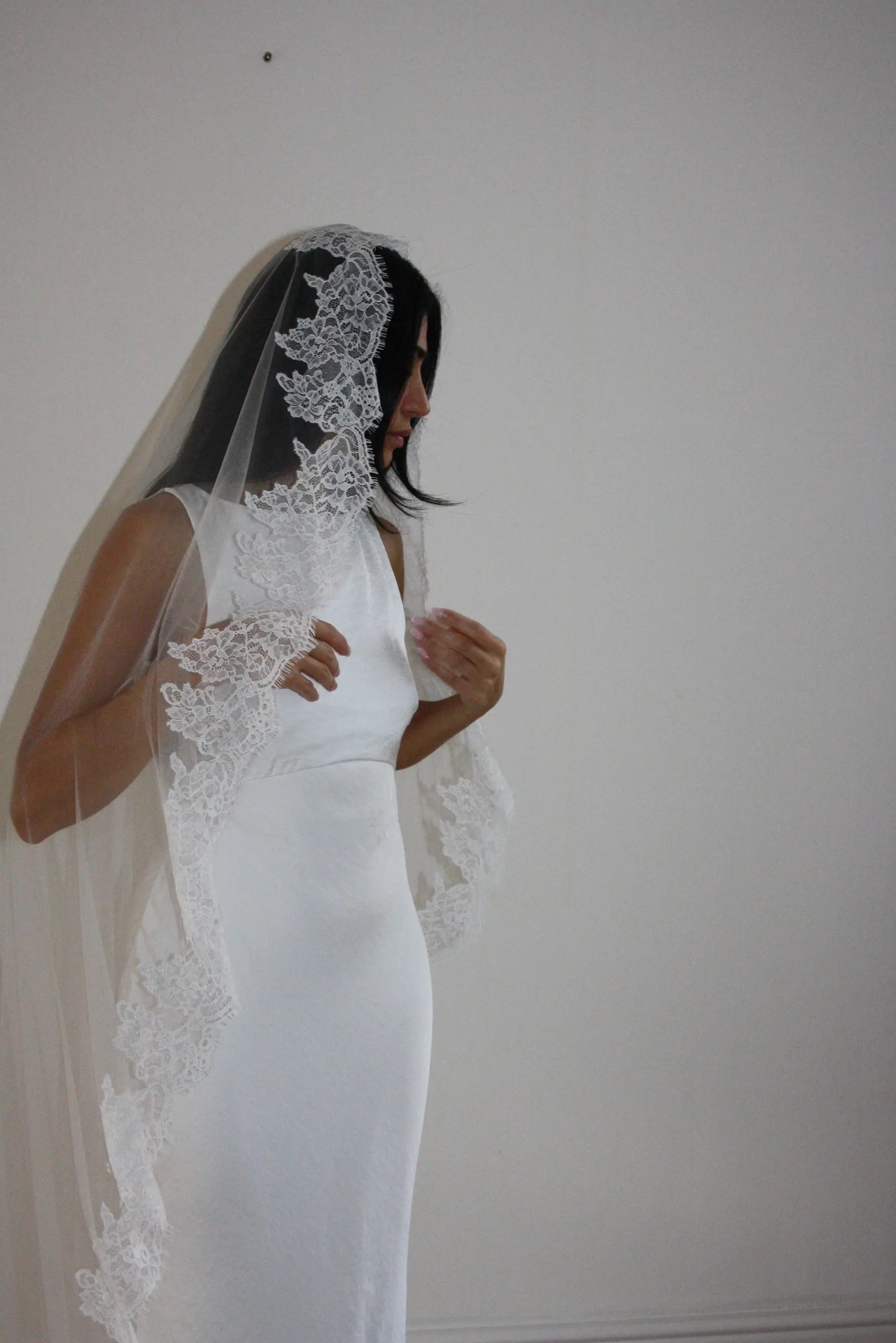 Soft off-white chapel bridal veil made from lightweight tulle with delicate lace trim along the edges for a dreamy, romantic look