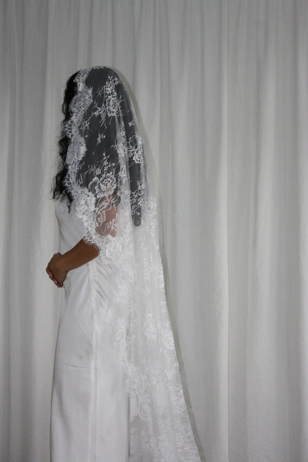 The Mantilla-Style Chantilly Rose Full Lace Veil is a cathedral-length bridal statement piece, designed for timeless elegance. Made from soft, lightweight tulle, it features intricate Chantilly rose lace that frames the veil completely, creating a delicate, romantic finish. The veil drapes beautifully straight to the ground, evoking a graceful, ethereal silhouette.This a vintage take on spanish style mantilla veil.