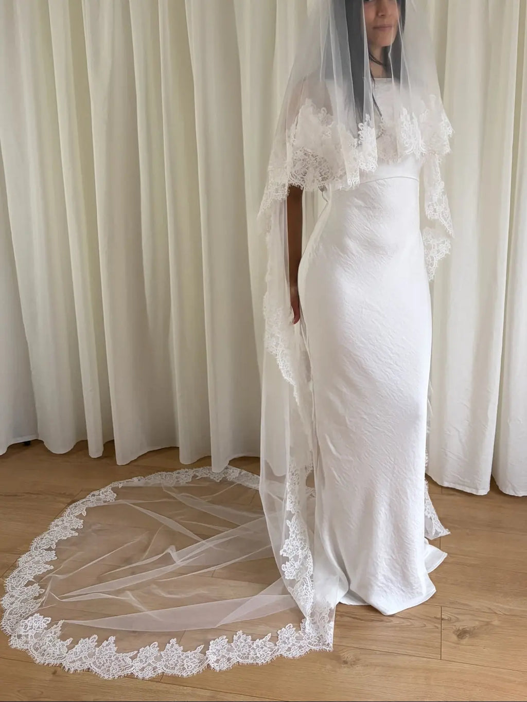 Soft off-white cathedral bridal veil made from lightweight tulle with delicate lace trim and a drop blusher, perfect for a dreamy, romantic look