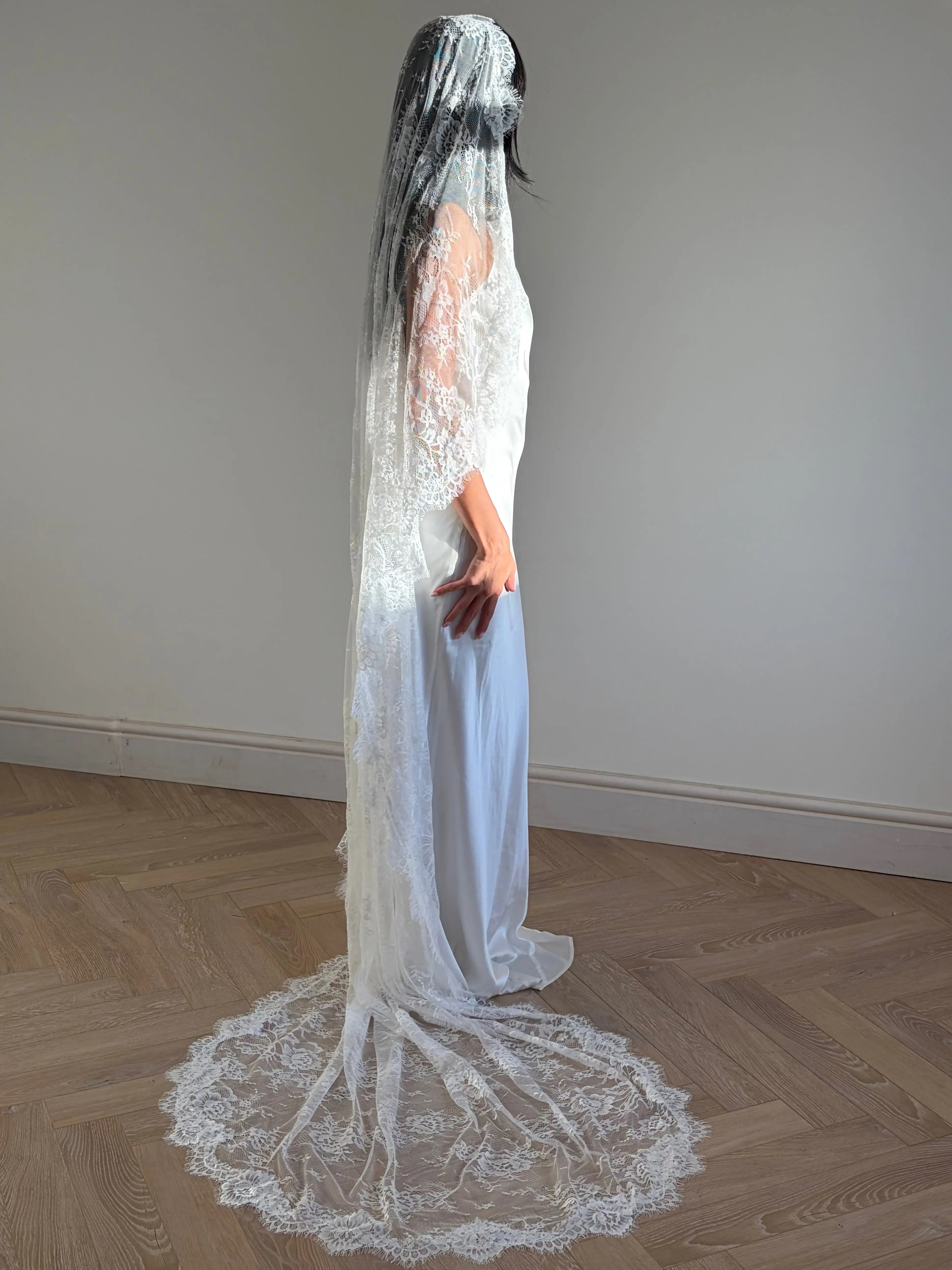 The Mantilla-Style Chantilly Rose Full Lace Veil is a cathedral-length bridal statement piece, designed for timeless elegance. Made from soft, lightweight tulle, it features intricate Chantilly rose lace that frames the veil completely, creating a delicate, romantic finish. The veil drapes beautifully straight to the ground, evoking a graceful, ethereal silhouette.This a vintage take on spanish style mantilla veil.