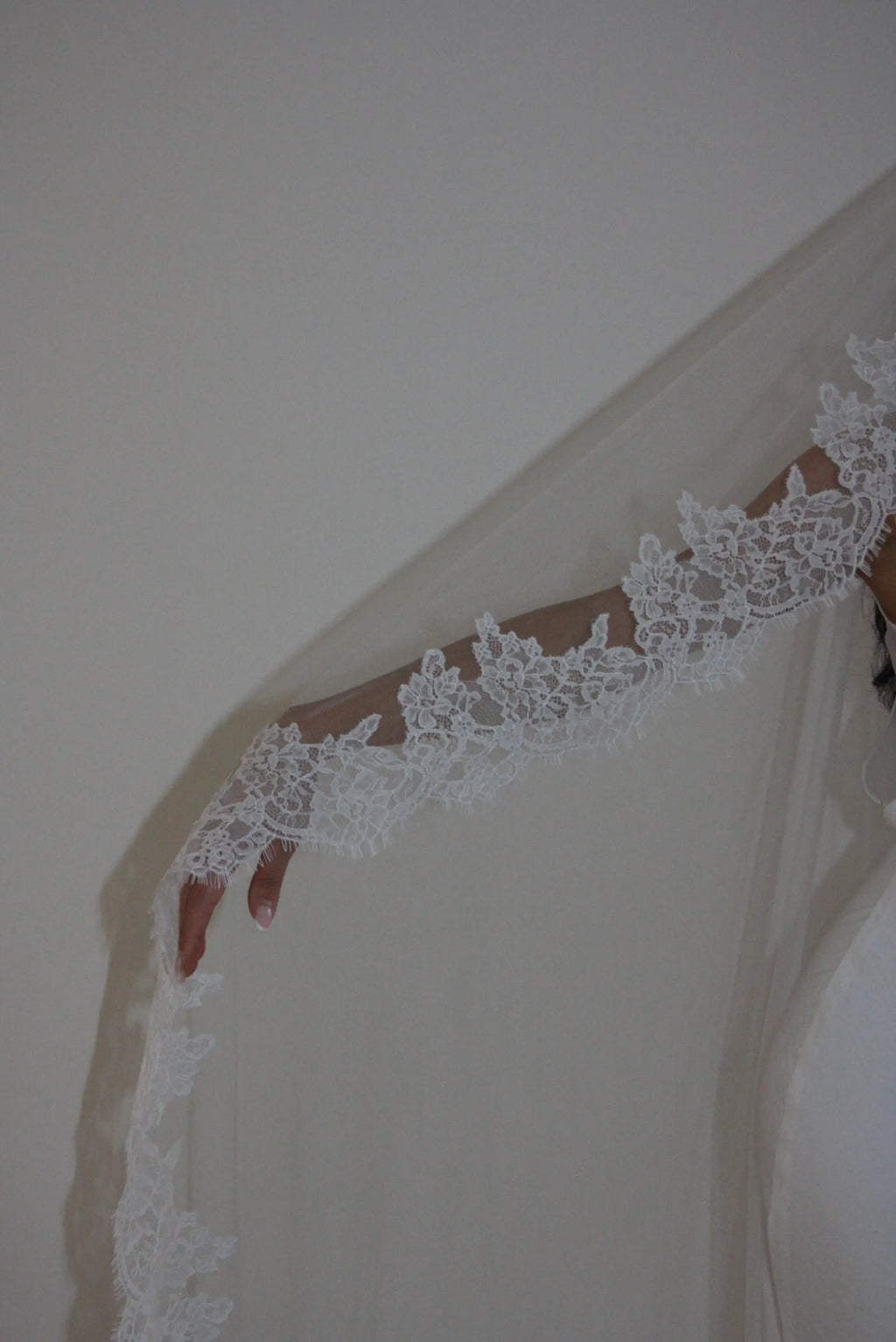 Soft off-white chapel bridal veil made from lightweight tulle with delicate lace trim along the edges for a dreamy, romantic look