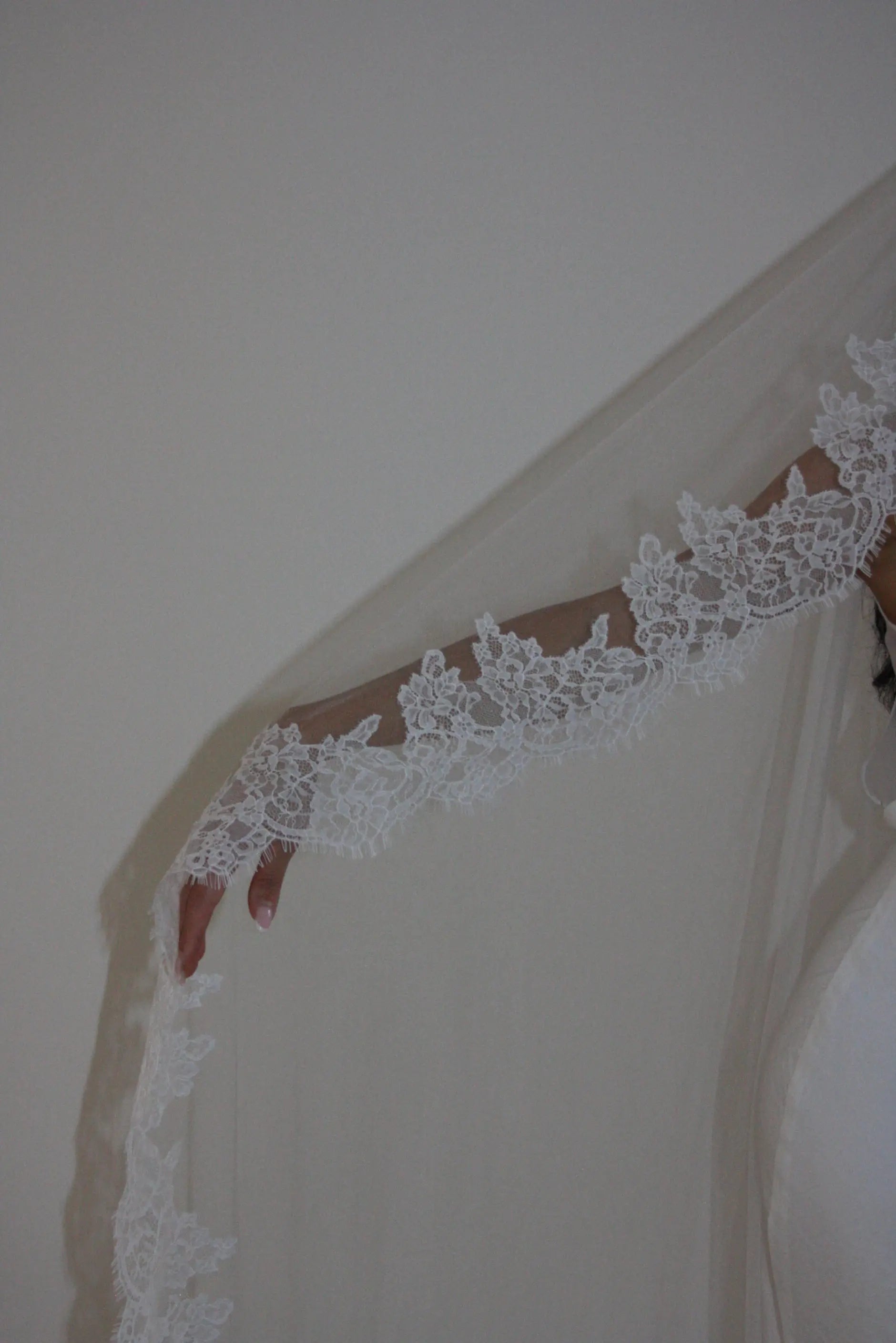 Soft off-white chapel bridal veil made from lightweight tulle with delicate lace trim along the edges for a dreamy, romantic look