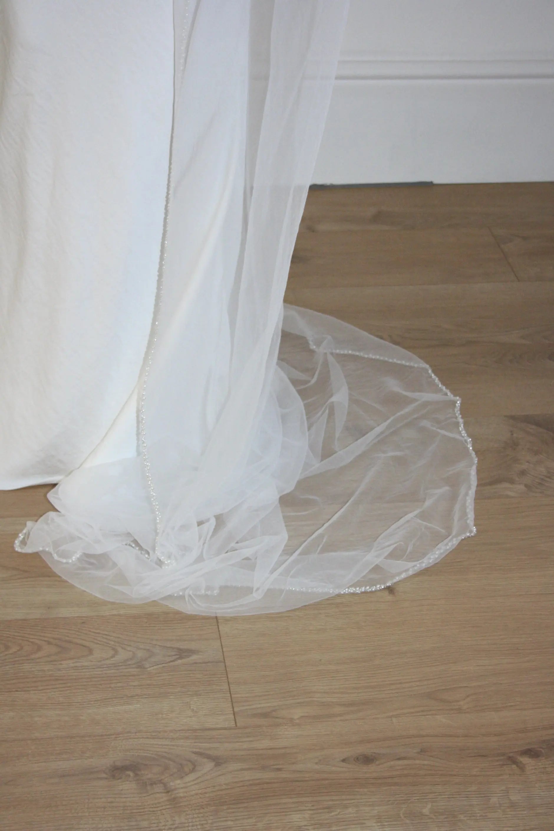 Soft tulle wedding veil with hand-placed pearl trim, perfect for modern and classic brides seeking an elegant bridal accessory