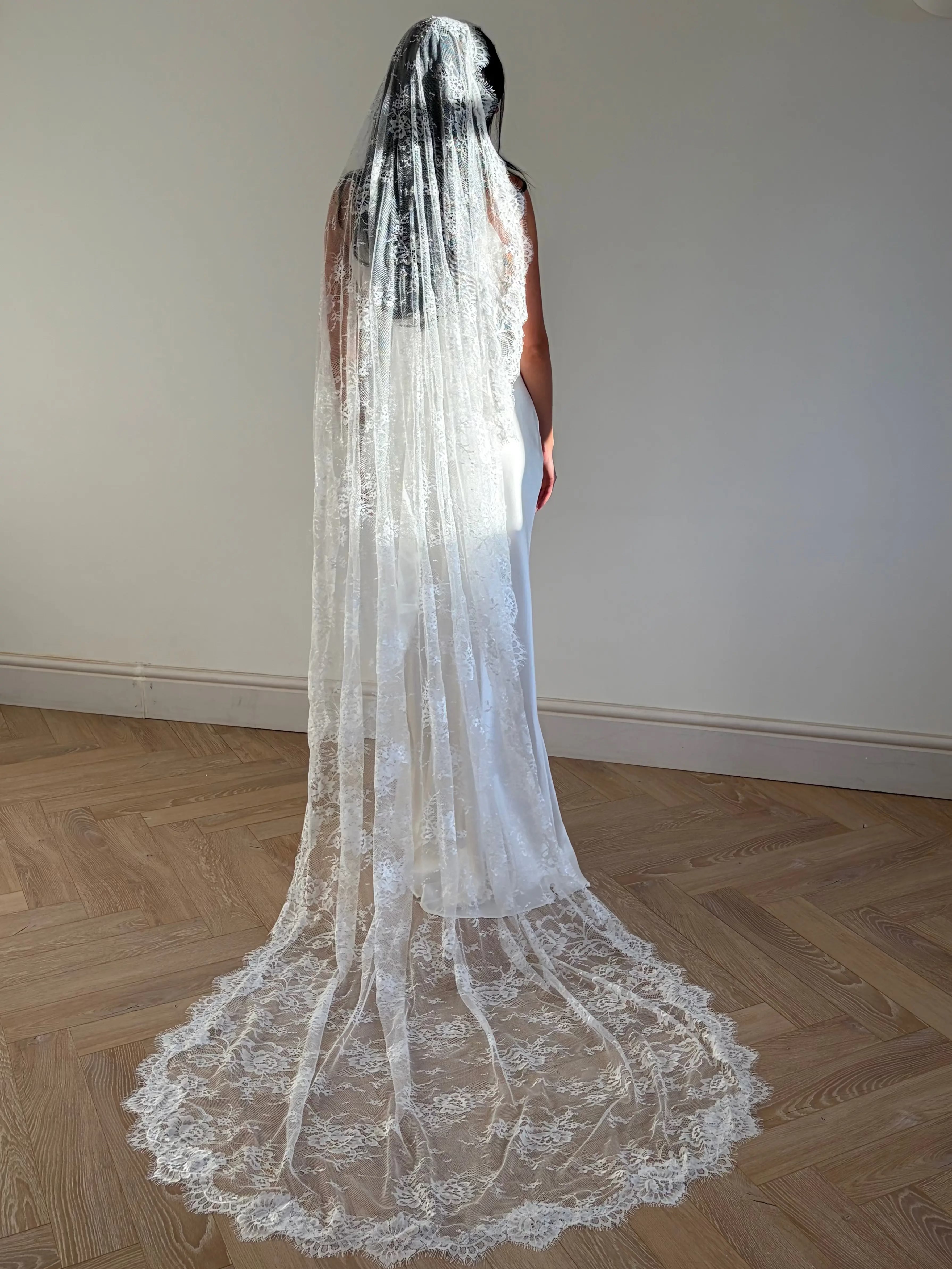 The Mantilla-Style Chantilly Rose Full Lace Veil is a cathedral-length bridal statement piece, designed for timeless elegance. Made from soft, lightweight tulle, it features intricate Chantilly rose lace that frames the veil completely, creating a delicate, romantic finish. The veil drapes beautifully straight to the ground, evoking a graceful, ethereal silhouette.This a vintage take on spanish style mantilla veil.