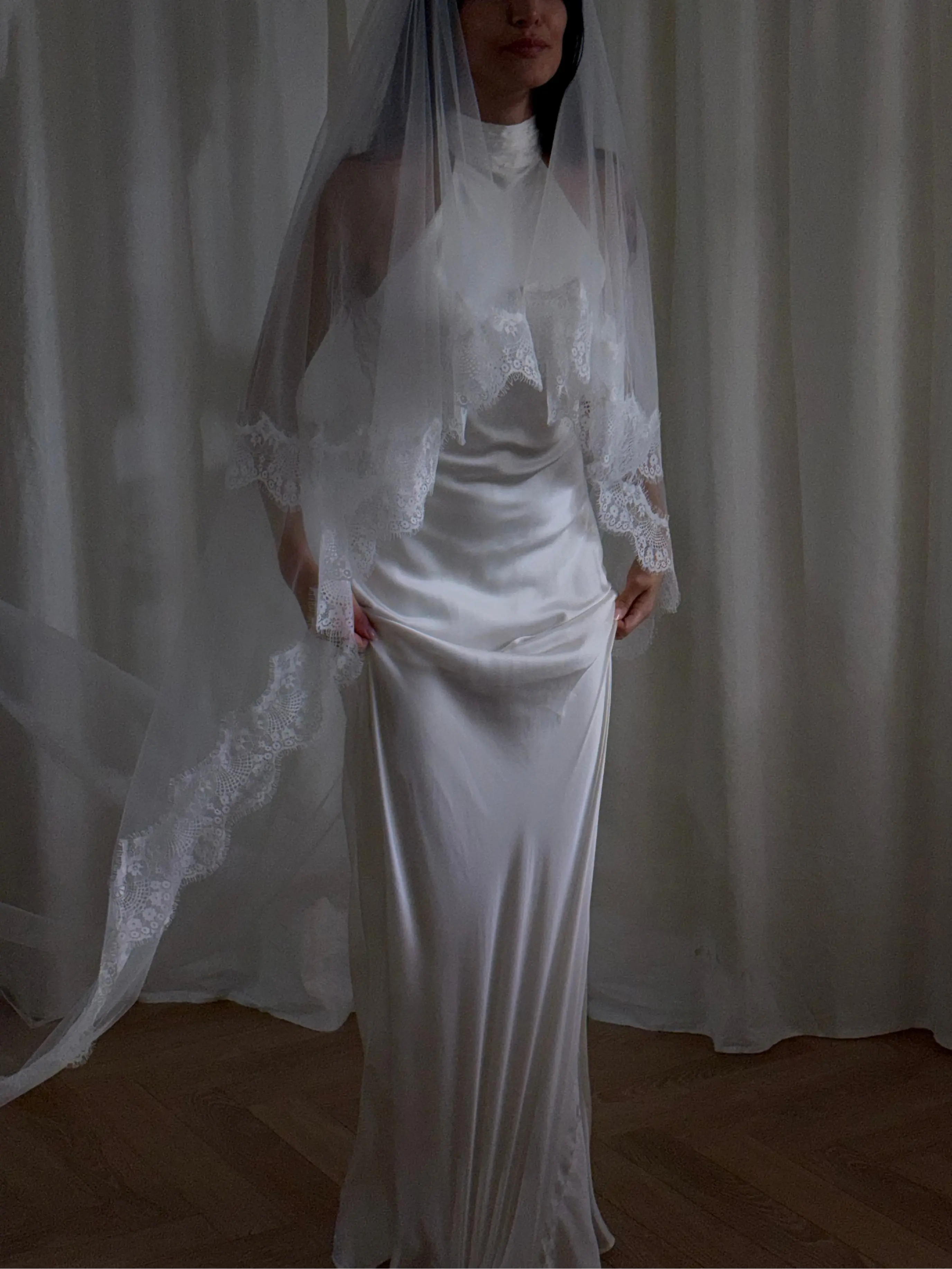 The Eyelash Trim Blusher Veil is a light, romantic accessory for modern brides seeking an ethereal finishing touch. Made from soft, flowing tulle, it features delicate eyelash lace along the edge for a subtle, feminine detail. The veil drapes softly over the face and shoulders, enhancing the bride’s silhouette with an airy, graceful effect. Its discreet comb attachment ensures a secure, seamless fit, making it ideal for both ceremony and photography. Perfect for adding a classic yet dreamy accent to any gow