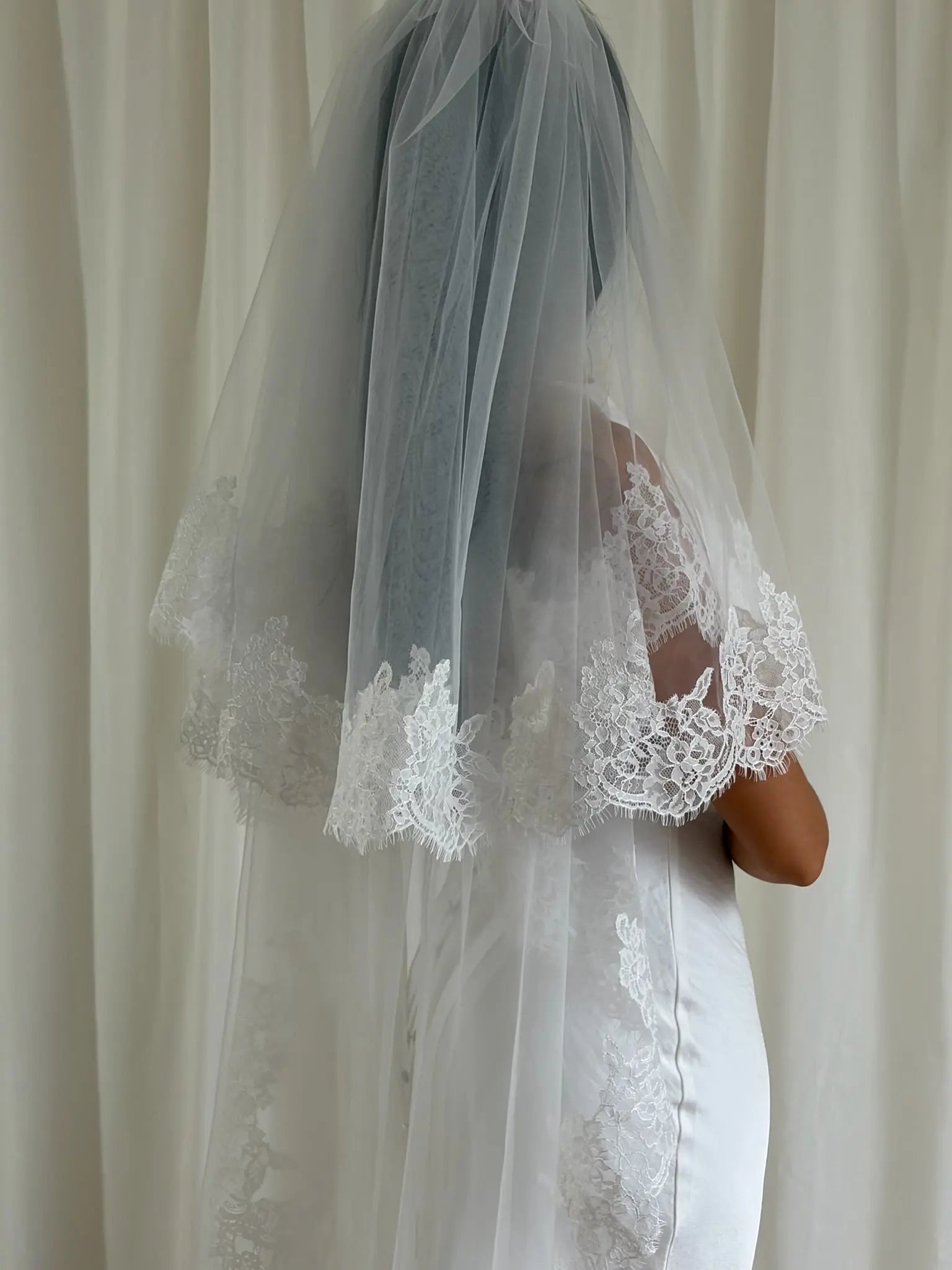 Soft off-white cathedral bridal veil made from lightweight tulle with delicate lace trim and a drop blusher, perfect for a dreamy, romantic look